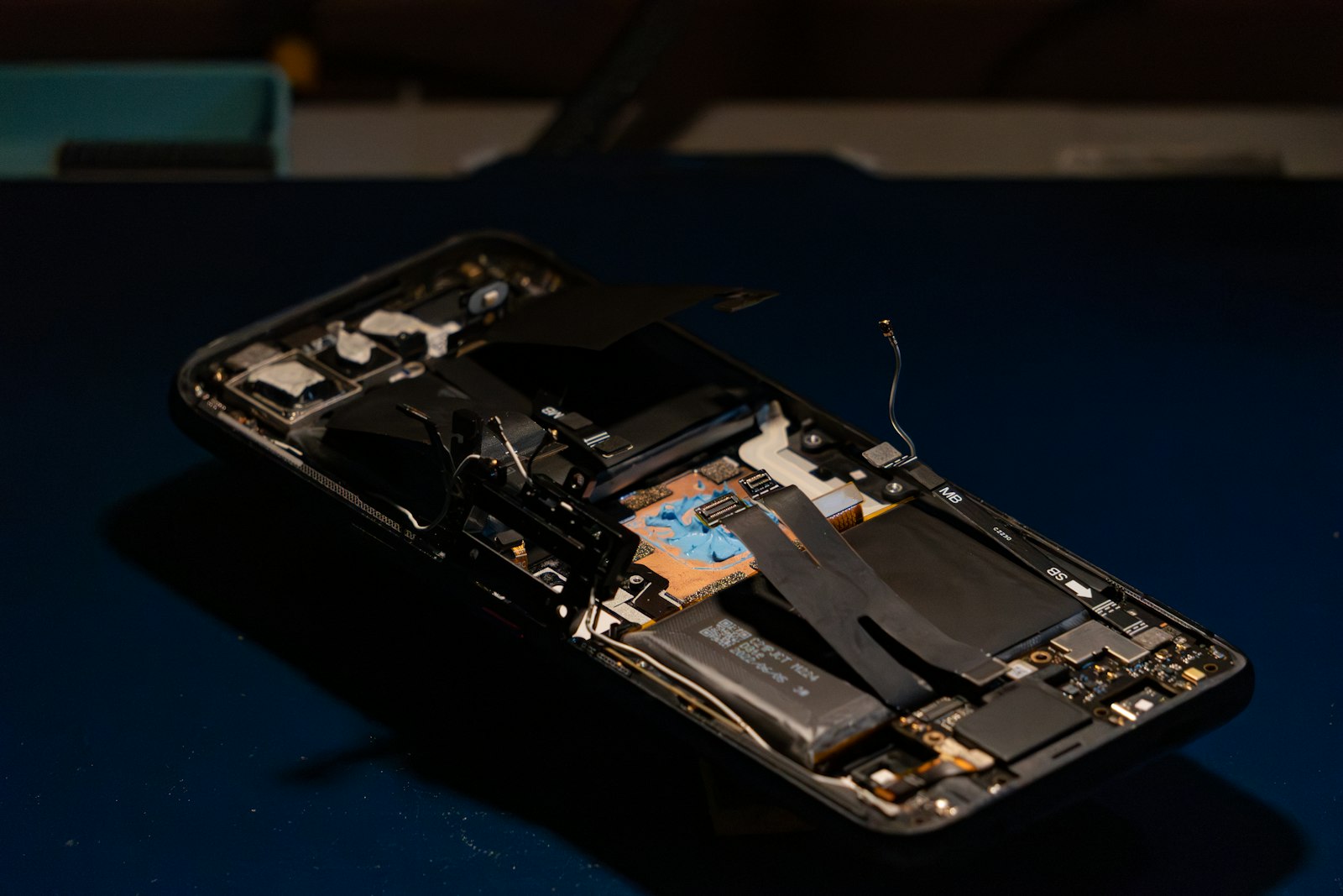 Celular desarmado sobre una mesa oscura de reparación